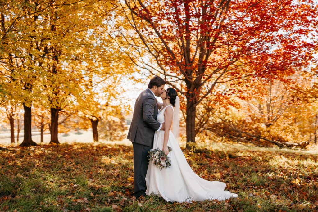 Bride and Groom kissing with fall trees in the background