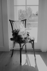 Black and white photo of a bridal bouquet resting on a wooden chair
